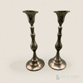 Baluster Brass Candlesticks- Pair. A pair of vintage brass candlesticks with a dark, polished metallic finish and some patina along the bass, standing side-by-side against a plain off-white background.