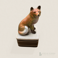 Clever Fox Trinket Box. A ceramic box with a red fox sitting on top of the lid. The base of the box is brown with two gold lines. The finish has a crazed finish.