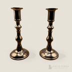 Georgian Style Brass Candlesticks. A pair of vintage brass candlesticks with a round base and warm metallic finish, standing side-by-side against a neutral beige background. A 'R&F FIELD FINDS' logo is visible in the bottom right corner