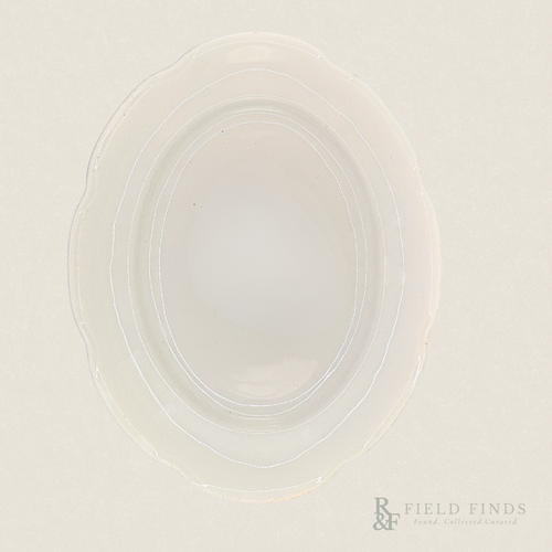 Antique White Ironstone Platter. An oval-shaped, translucent white ironstone platter with a scalloped rim, photographed from directly above on a matching off-white background. A 'Field Finds' logo is visible in the bottom right corner.