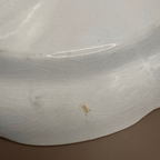 Antique White Ironstone Platter. Close-up of a glossy white  platter with a prominent crackle glaze pattern and a small brown stain near the center.