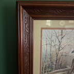 Close up of cream matting and corner of dark carved wood-style frame.