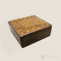 Vintage rectangular wooden trinket box featuring a decorative floral inlay in golden yellow and fine white geometric borders. The box has a warm brown wood finish with visible signs of age and wear, photographed against a soft ivory background.