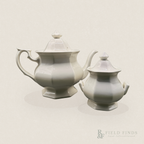 English Ironstone Teapot & Sugar Bowl — W.T. Adams & Sons. A white ironstone teapot and matching sugar bowl set with a glossy finish, photographed against a solid light beige background. The teapot is positioned behind the sugar bowl, and a 'Field Finds' logo watermark is visible in the bottom right corner.